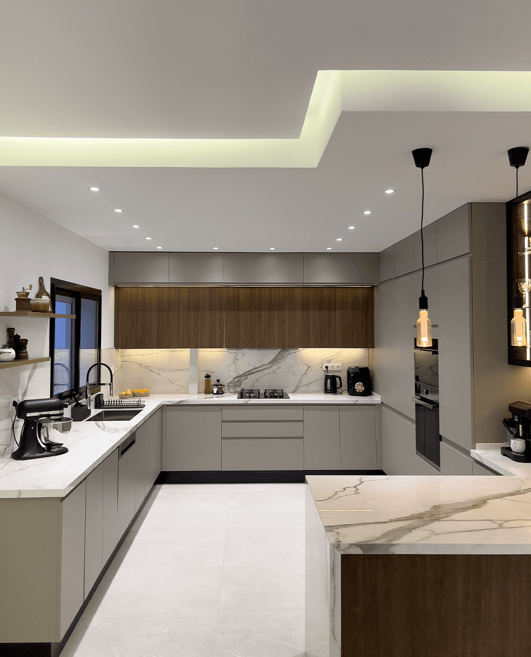 Cuisine Cuisina contemporaine avec façades gris taupe, éléments en bois, îlot effet marbre et éclairage intégré.